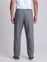 A person shown from the back wearing gray pull-on pants with a white t-shirt and dark sneakers, photographed against a light gray studio background.  | Fog