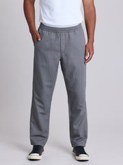 A person wearing gray pull-on trousers with a white t-shirt and black sneakers, shown from the waist down against a light gray studio background. | Fog