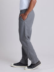 A person shown from the waist down wearing gray pull-on trousers, a white t-shirt, and black canvas sneakers against a light gray studio background. | Fog
