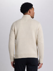 A man viewed from the back wearing a cream-colored knit mock neck sweater and black trousers, set against a plain light gray studio background. | Chai