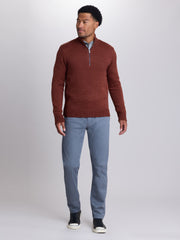 A man modeling a rust-brown half-zip knit sweater, paired with light blue trousers, a light blue collared shirt, and black sneakers, against a neutral gray studio background. | Redwood