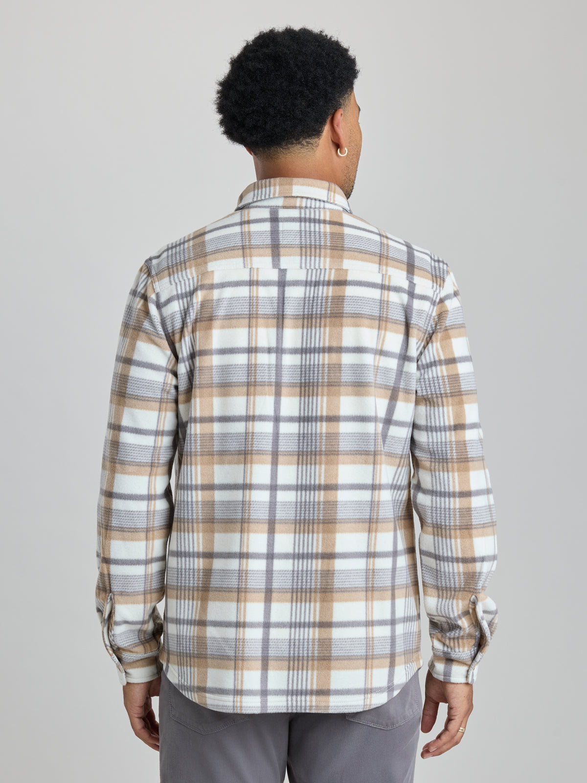 A man viewed from behind wearing a long-sleeve plaid button-up shirt in beige, white, and gray, paired with gray trousers, against a solid light gray background. | Steam