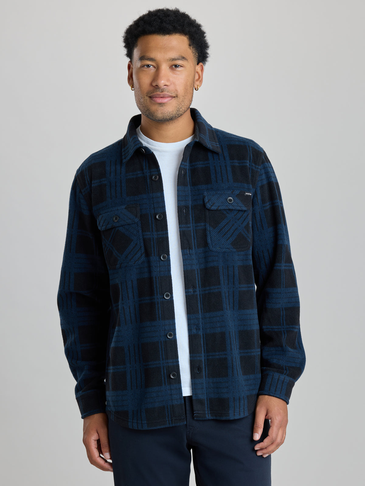 A man wearing a dark navy and black plaid button-up shirt jacket over a white t-shirt, photographed against a solid light gray studio background. |  True Navy