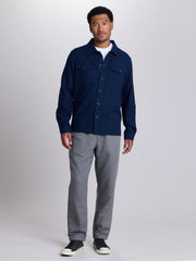 A man modeling a dark navy blue button-up shirt jacket over a white t-shirt, paired with gray pants and black sneakers, against a light gray studio background. | Midnight