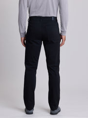 Rear view of a person wearing black trousers, a light gray long-sleeve shirt, and gray shoes against a plain light gray studio background. | Black