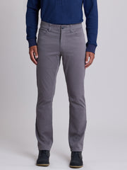 A person wearing slim-fit gray trousers, a navy blue long-sleeve shirt, and dark shoes, standing against a light gray studio background. | Grey Goose