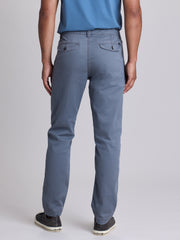 Rear view of a person wearing slate blue straight-leg chinos with a blue shirt and dark sneakers, photographed against a neutral gray studio  background. | Condor